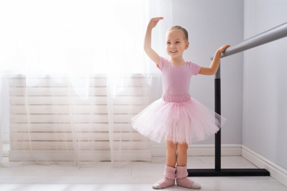 Cute little girl dreams of becoming a ballerina. Child girl in a pink tutu dancing in a room. Baby girl is studying ballet.