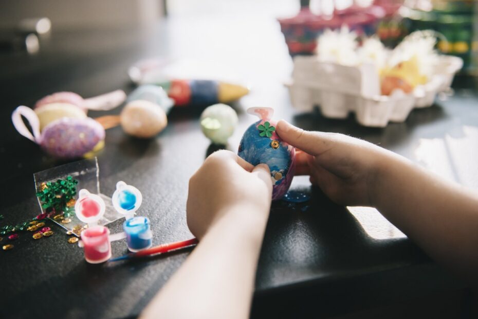 A child decorating eggs at Easter with glitter, glue and paint.